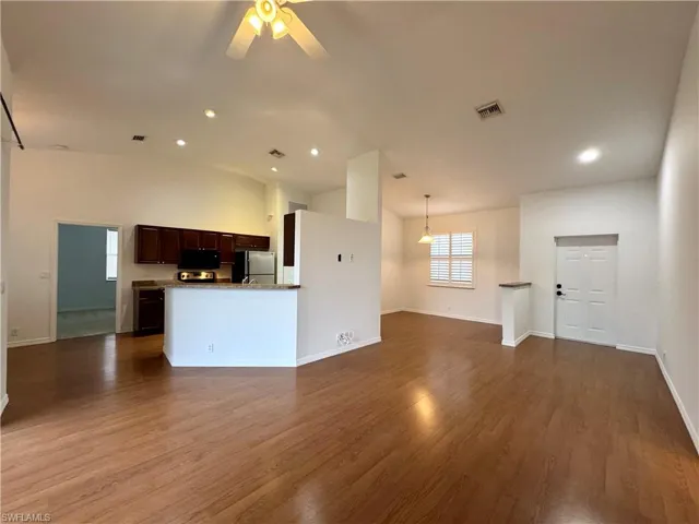 Unfurnished living room featuring ceiling fan, lofted ceiling, and hardwood / wood-style flooring