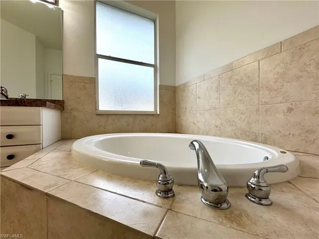 Bathroom featuring a wealth of natural light, a tub to relax in, and vanity