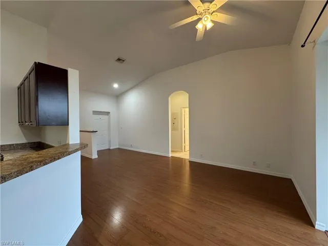 Unfurnished living room with ceiling fan, hardwood / wood-style floors, and lofted ceiling