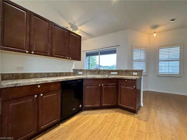Kitchen with sink, dark brown cabinetry, dishwasher, and light hardwood / wood-style flooring