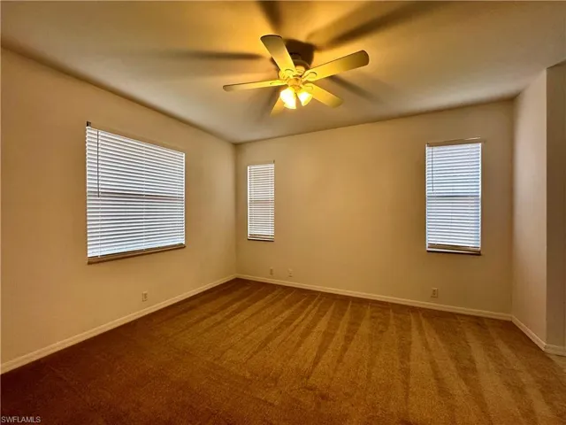 Carpeted empty room featuring ceiling fan