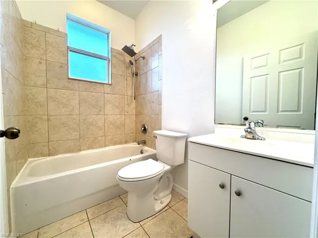 Full bathroom featuring toilet, tiled shower / bath, tile patterned floors, and vanity