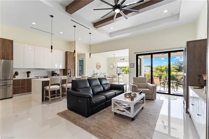 Living room featuring a towering ceiling, beamed ceiling, light tile patterned flooring, recessed lighting, and a ceiling fan