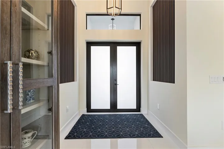Tiled foyer entrance with baseboards and french doors