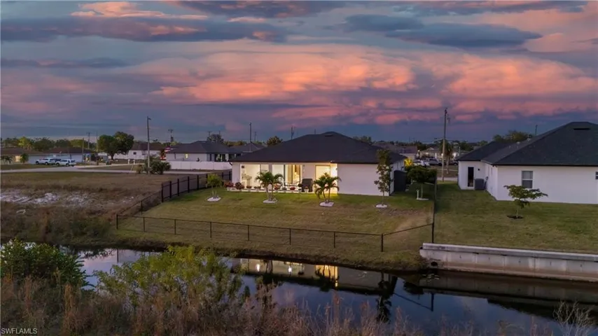 Back of house with a water view, a fenced backyard, and a patio area