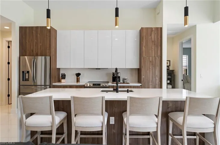 Kitchen with white cabinets, hanging light fixtures, appliances with stainless steel finishes, and modern cabinets