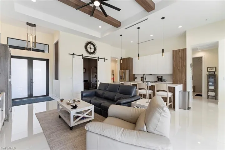 Living area featuring a towering ceiling, recessed lighting, beamed ceiling, a barn door, and light tile patterned floors
