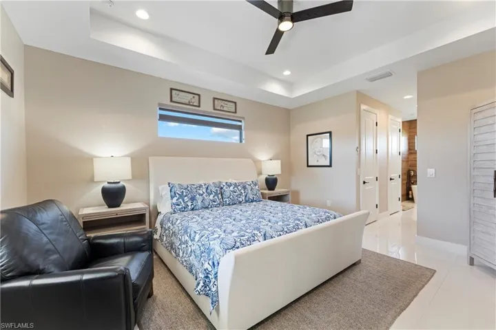 Bedroom with a closet, a ceiling fan, recessed lighting, light tile patterned floors, and a raised ceiling