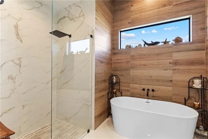 Full bath featuring a soaking tub and a marble finish shower