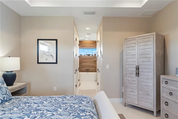 Bedroom with light tile patterned flooring, recessed lighting, and ensuite bathroom
