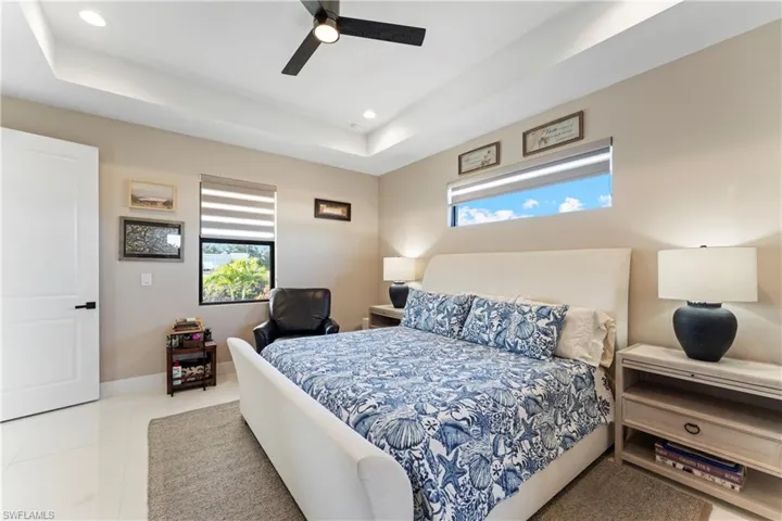 Bedroom featuring a raised ceiling, light tile patterned floors, ceiling fan, and recessed lighting