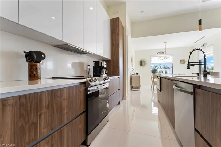 Kitchen featuring modern cabinets, white cabinetry, appliances with stainless steel finishes, and pendant lighting