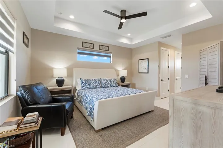 Bedroom with a tray ceiling, ceiling fan, recessed lighting, and light tile patterned flooring
