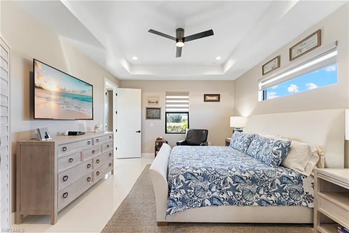 Bedroom with a ceiling fan, light tile patterned floors, recessed lighting, and a raised ceiling