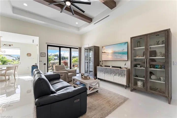 Living room with a high ceiling, light tile patterned floors, ceiling fan, a raised ceiling, and recessed lighting