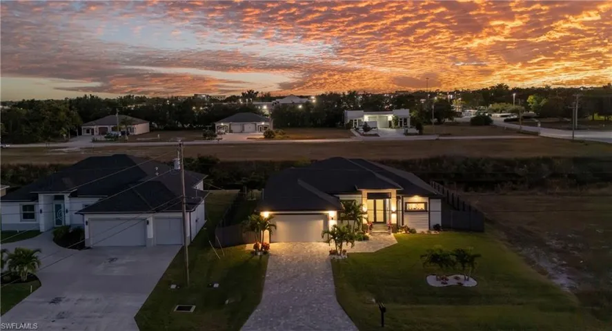 View of front of home featuring decorative driveway, a garage, a lawn, and a residential view