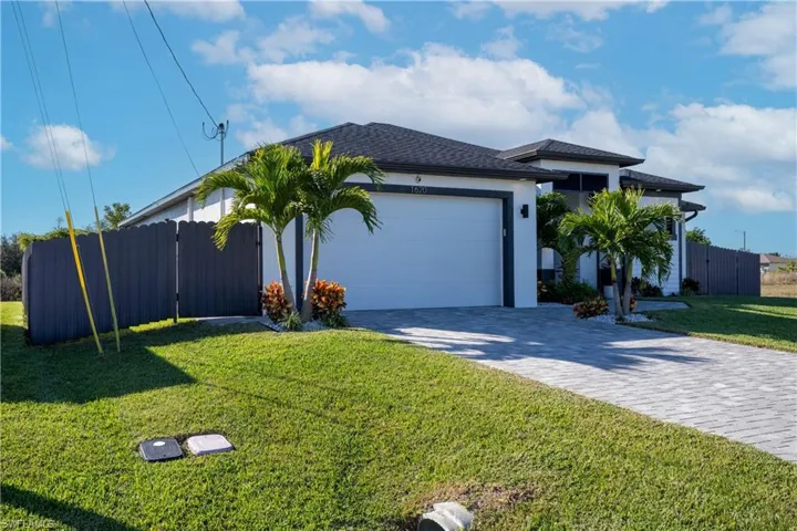 View of front of property with decorative driveway, a garage, stucco siding, and a gate