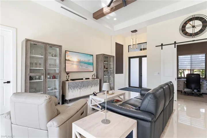 Living room featuring a towering ceiling, a barn door, a desk, french doors, and recessed lighting