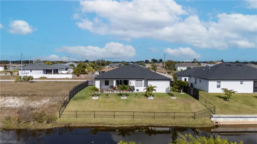 Rear view of property featuring a water view, a residential view, and a fenced backyard