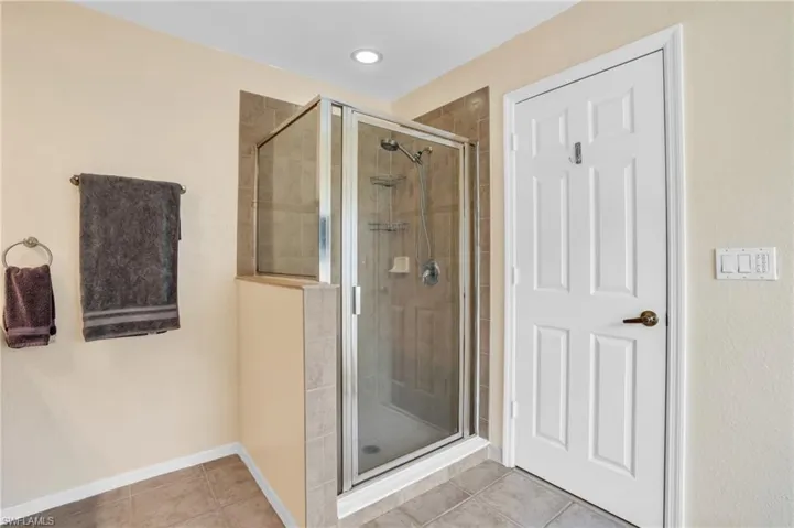 Bathroom featuring a shower with shower door and tile patterned floors