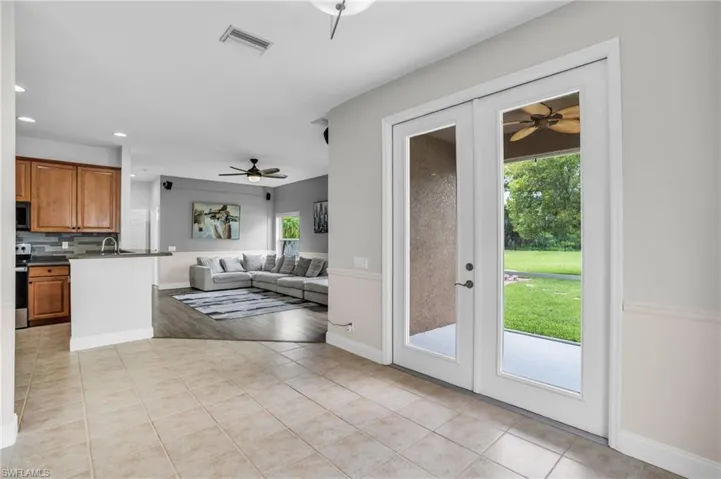 Kitchen featuring light tile patterned flooring, ceiling fan, range, french doors, and backsplash
