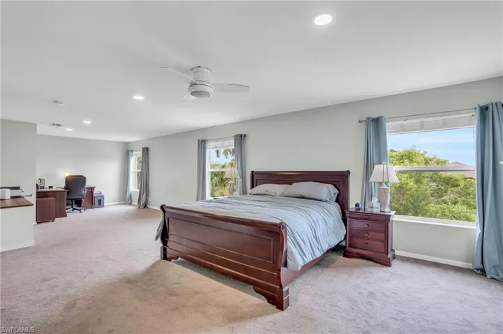 Bedroom featuring multiple windows, ceiling fan, and carpet flooring
