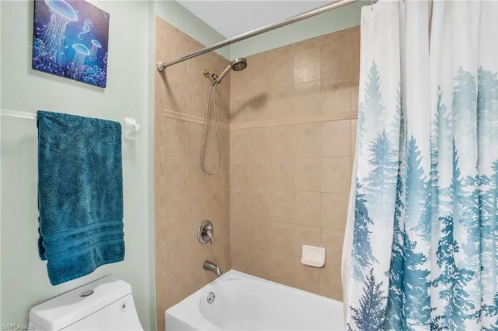 Bathroom with toilet and shower / bathtub combination with curtain