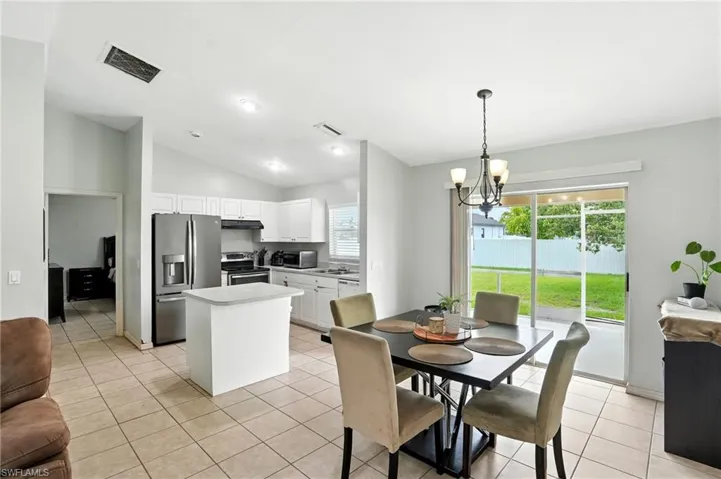 Dining space featuring light tile patterned flooring, lofted ceiling, a chandelier, and recessed lighting