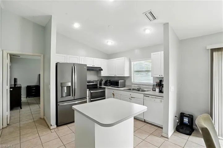 Kitchen with stainless steel appliances, white cabinetry, a kitchen island, light countertops, and light tile patterned floors