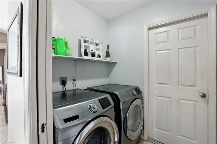 Laundry area featuring light tile patterned flooring and washer and clothes dryer