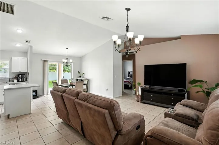 Living area featuring a chandelier, light tile patterned floors, lofted ceiling, and plenty of natural light