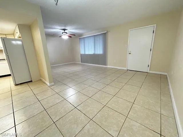 Unfurnished room with a textured ceiling, a ceiling fan, and light tile patterned flooring