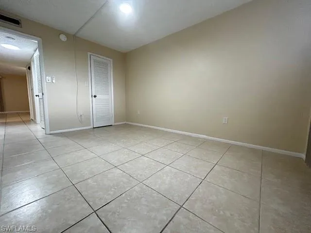 Unfurnished room with light tile patterned floors and baseboards