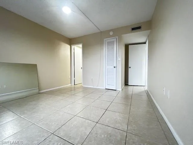 Unfurnished bedroom with light tile patterned floors, a textured ceiling, and a closet