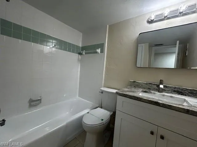 Full bathroom with a textured wall, vanity, and shower / bathtub combination