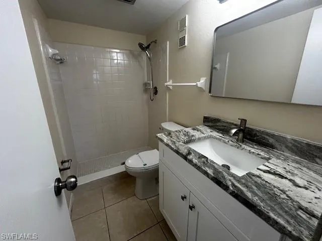 Full bath with vanity, a shower stall, and light tile patterned floors