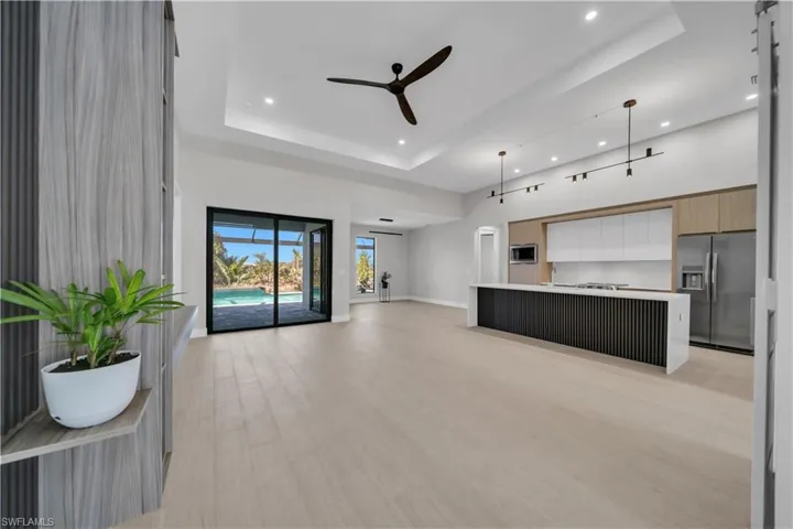 Unfurnished living room featuring ceiling fan, a raised ceiling, light wood-style flooring, and recessed lighting