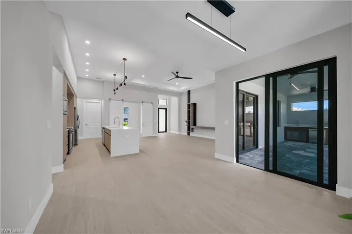 Unfurnished living room with a barn door, light wood-style floors, recessed lighting, and healthy amount of natural light