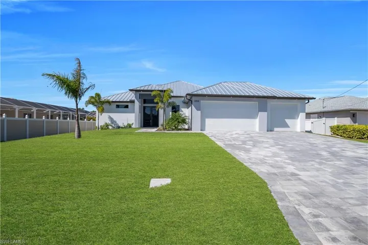 View of front facade with a standing seam roof, decorative driveway, a garage, and stucco siding