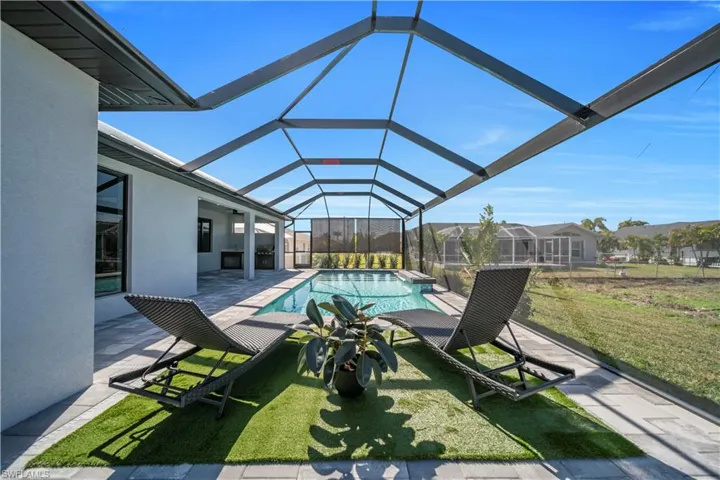 Outdoor pool with a patio area, a sunroom, a lanai, and a lawn