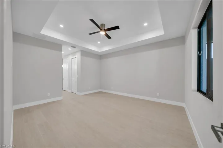 Unfurnished room with ceiling fan, recessed lighting, light wood-style floors, and a raised ceiling