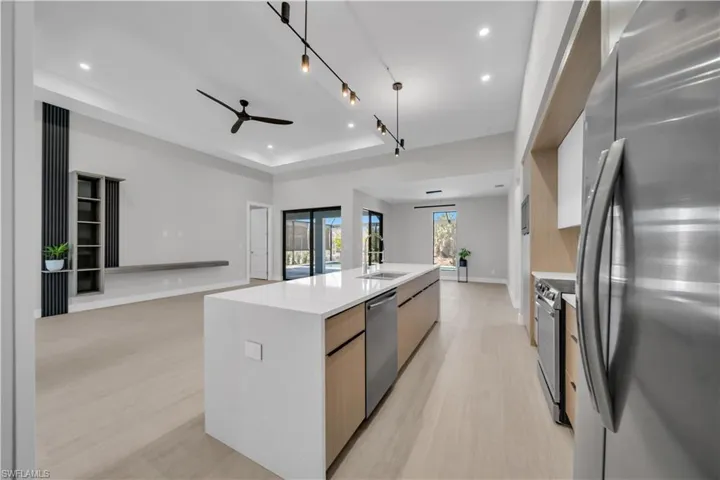 Kitchen with stainless steel appliances, modern cabinets, an island with sink, open floor plan, and two tone cabinetry