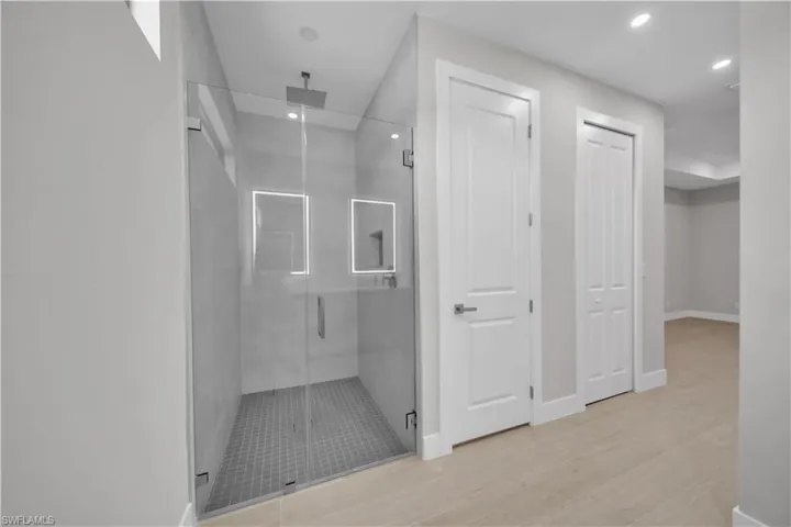 Bathroom with a stall shower, recessed lighting, light wood-style floors, and a closet