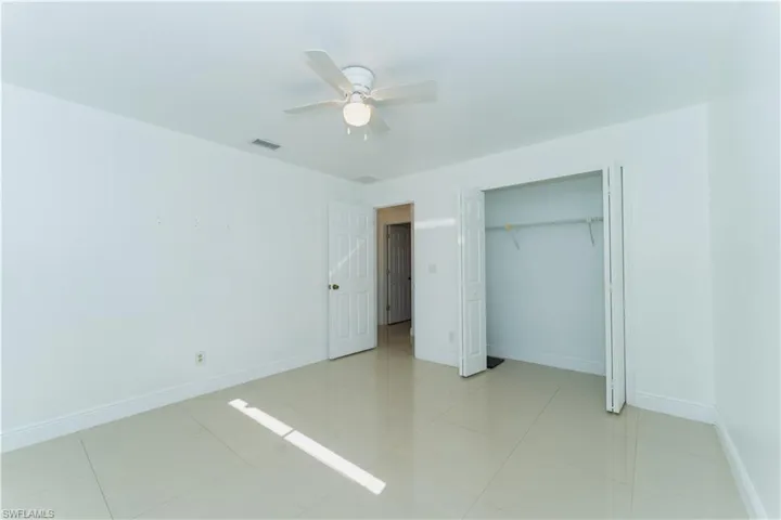 Unfurnished bedroom featuring a ceiling fan, a closet, and light tile patterned floors