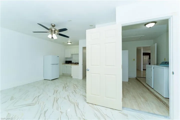 Empty room featuring washer and dryer, light marble finish floors, and ceiling fan