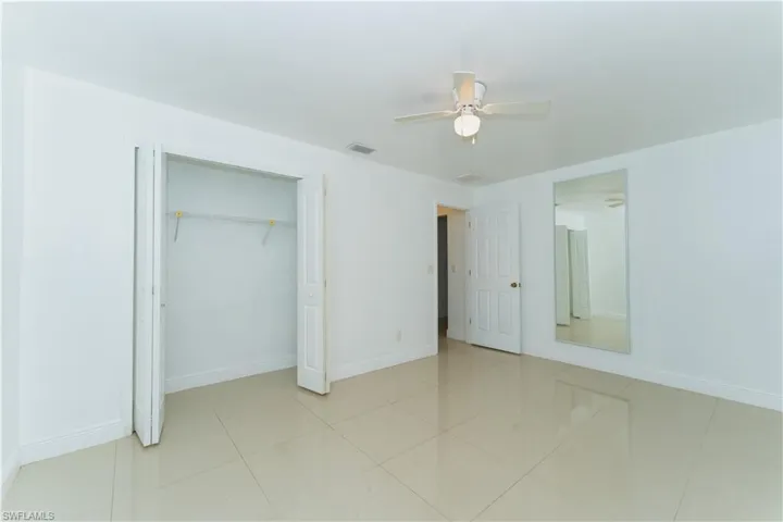 Unfurnished bedroom with ceiling fan, a closet, and light tile patterned flooring