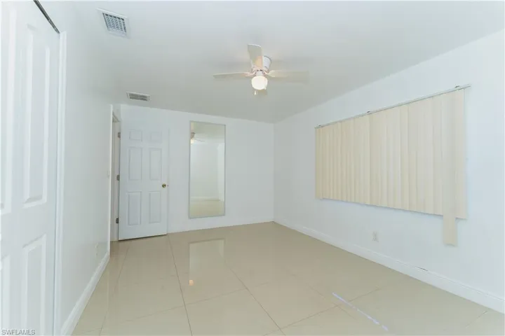 Empty room with light tile patterned floors and a ceiling fan