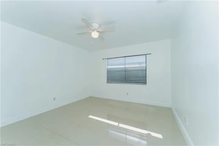 Empty room with light tile patterned floors and ceiling fan