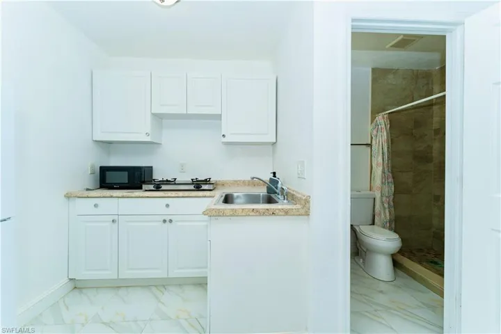 Kitchen with light marble finish floors, white cabinetry, and light countertops