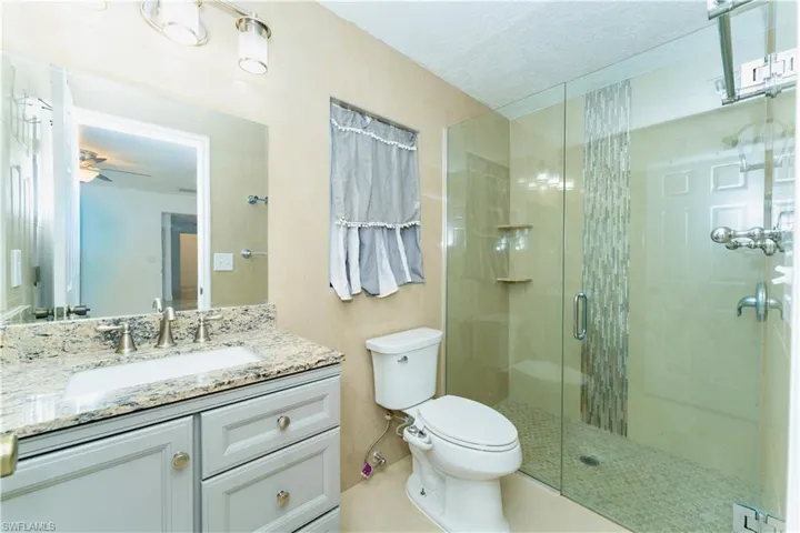 Bathroom with a stall shower, vanity, a textured ceiling, and light tile patterned floors